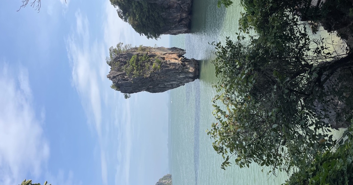 A karst islet rising from an emerald-green bay, beneath a clear sky